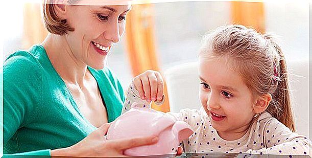 Mother teaching daughter to save with the piggy bank.