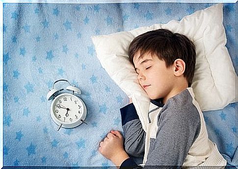 child sleeping with his alarm clock