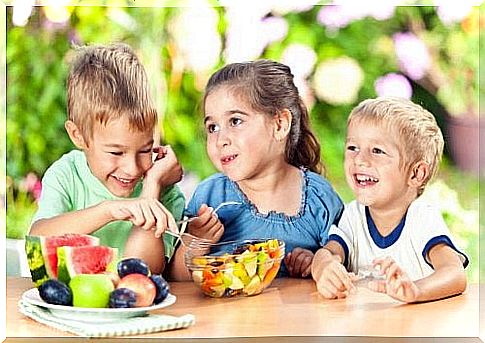 Three children together eating a fruit salad