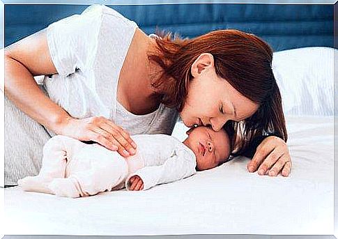 mother kissing newborn daughter